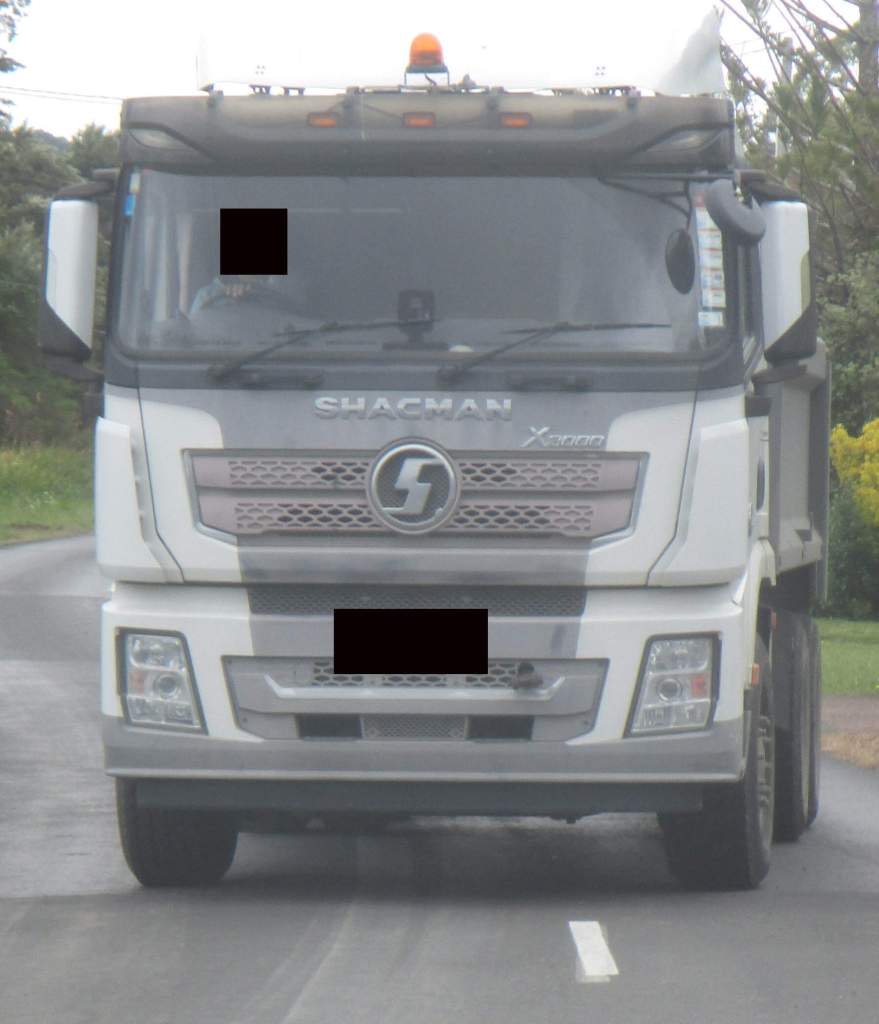 Unmarked dump truck drives around roads of West Auckland and Waitākere Ranges heritage area inconspicuously carrying out illegal dumping that looks like legitimate waste work.